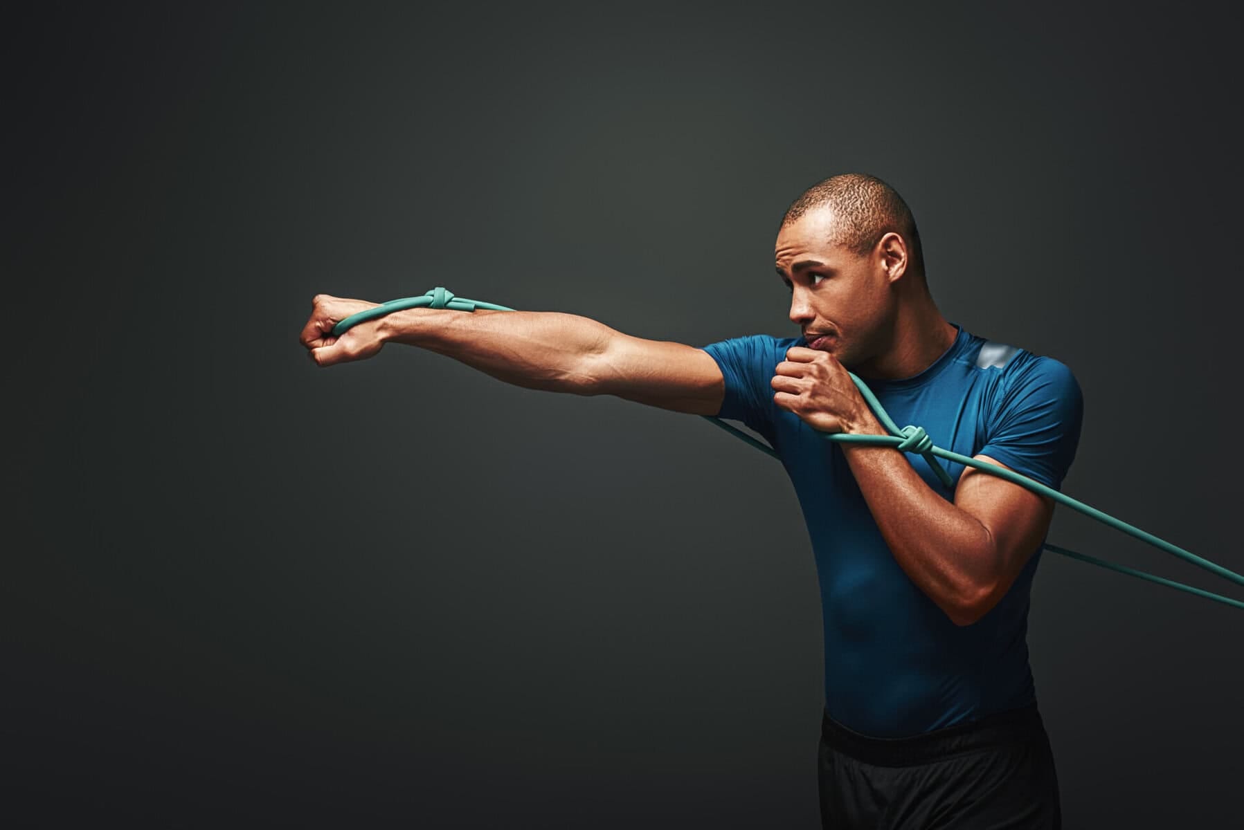 full of energy. sportsman working out with resistance band over dark background